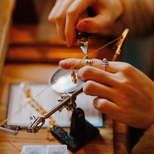 Person working on jewelry with tools and materials on a wooden table
